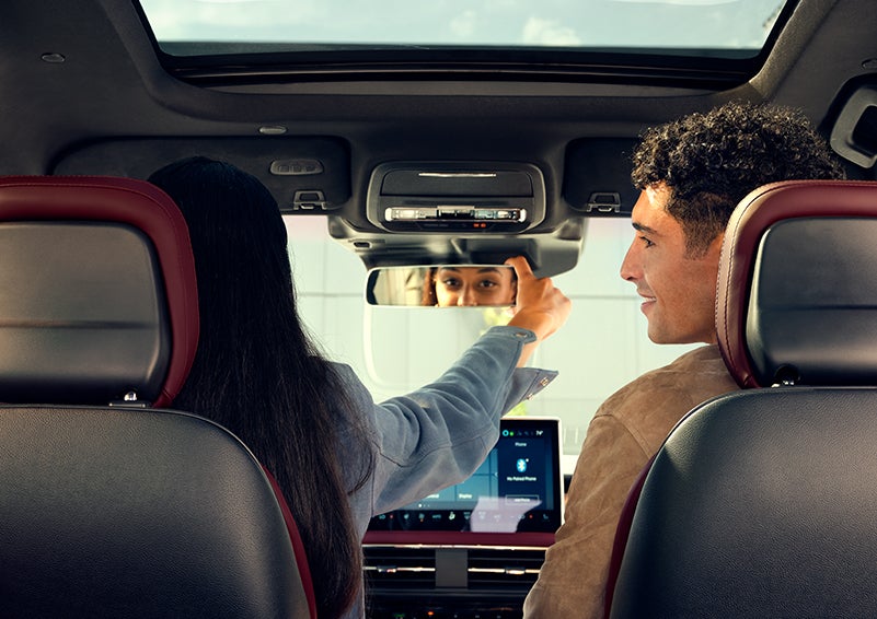 The driver of a 2023 Lincoln Corsair® SUV is shown adjusting the available frameless rearview mirror. | Angela Krause Lincoln of Alpharetta in Alpharetta GA
