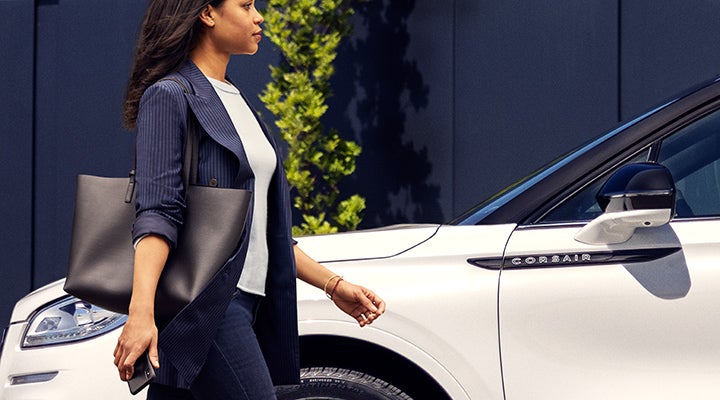 A woman approaches a 2024 Lincoln Corsair® SUV while holding a smartphone. | Angela Krause Lincoln of Alpharetta in Alpharetta GA