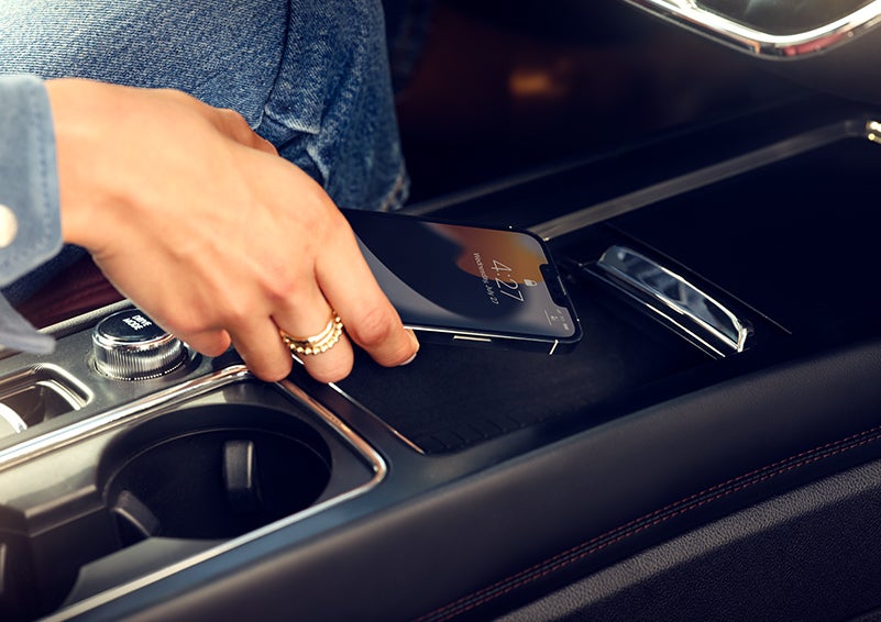 A smartphone is is being placed on the wireless charging pad in the front center console cubby. | Angela Krause Lincoln of Alpharetta in Alpharetta GA