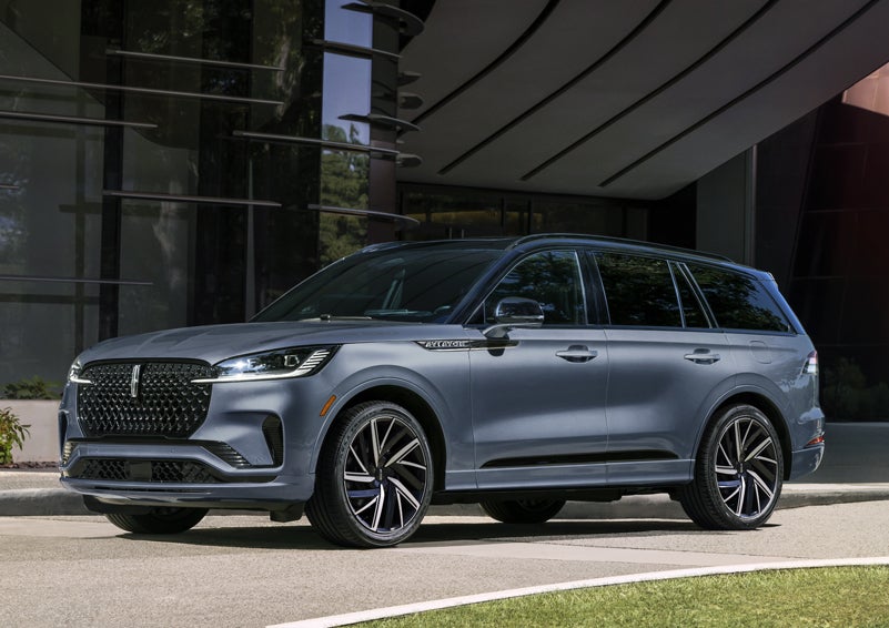 A gray 2025 Lincoln Aviator® SUV is parked outside a modern building showcasing the driver’s side of the vehicle. | Angela Krause Lincoln of Alpharetta in Alpharetta GA