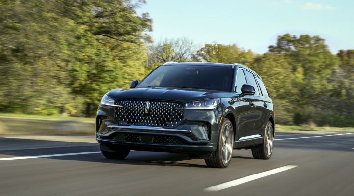 A 2025 Lincoln Black Label Aviator® SUV is being driven down a road lined with trees. | Angela Krause Lincoln of Alpharetta in Alpharetta GA
