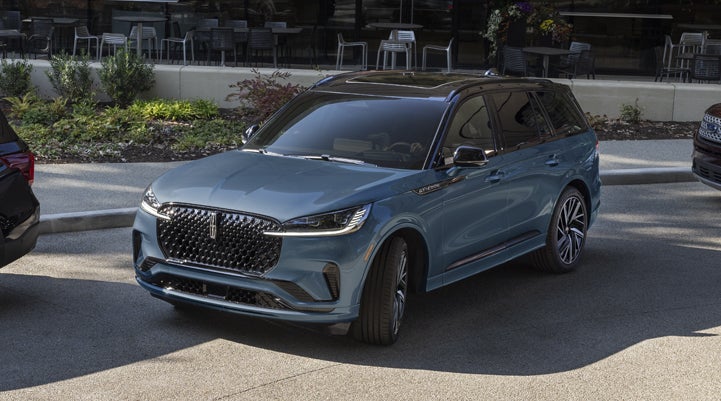 A Whisper Blue 2025 Lincoln Aviator® SUV is parked outside a modern building showcasing the driver’s side of the vehicle. | Angela Krause Lincoln of Alpharetta in Alpharetta GA
