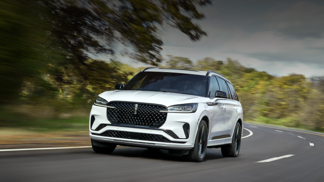 A white 2025 Lincoln Aviator® SUV is being driven down a road lined with trees. | Angela Krause Lincoln of Alpharetta in Alpharetta GA