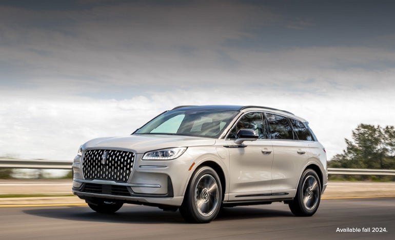 A 2025 white Lincoln Corsair® Grand Touring Plug-in Hybrid SUV is being driven down a highway