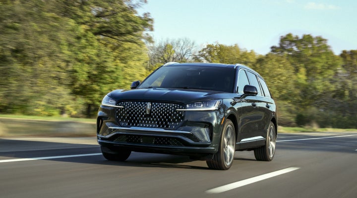 A 2026 Lincoln Black Label™ Aviator® SUV is being driven down a road lined with trees. | Angela Krause Lincoln of Alpharetta in Alpharetta GA