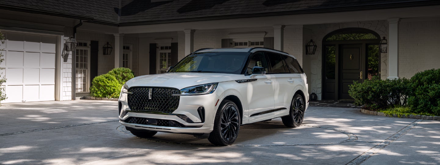 A white 2026 Lincoln Aviator® SUV is parked in the driveway of a luxury home. | Angela Krause Lincoln of Alpharetta in Alpharetta GA